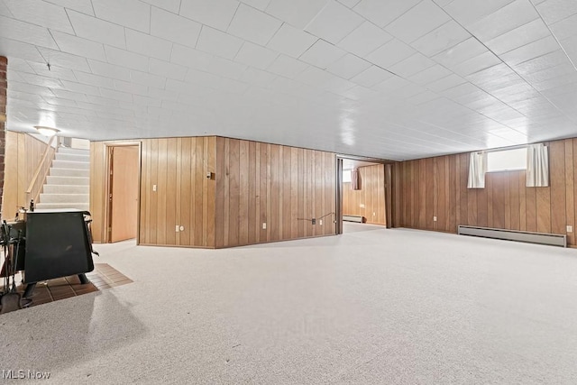 basement featuring wooden walls, dark carpet, and a baseboard heating unit