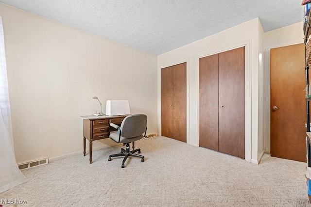 carpeted home office featuring a textured ceiling