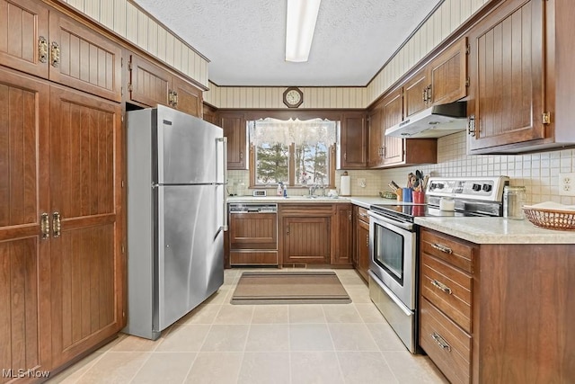 kitchen with a textured ceiling, light tile patterned floors, stainless steel appliances, and tasteful backsplash