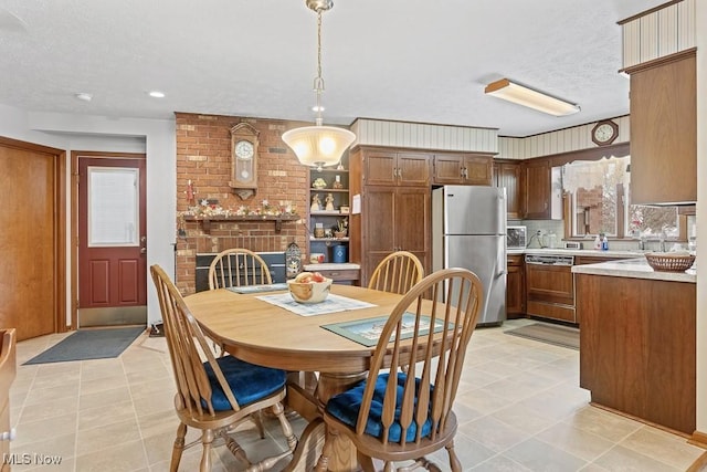 dining area with a textured ceiling, a brick fireplace, and light tile patterned flooring