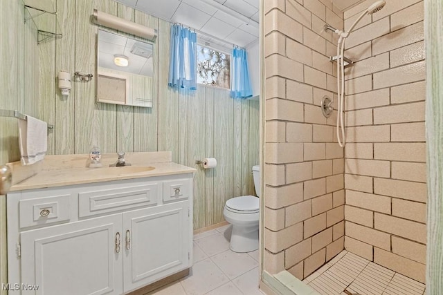 bathroom with tile patterned flooring, vanity, toilet, and tiled shower