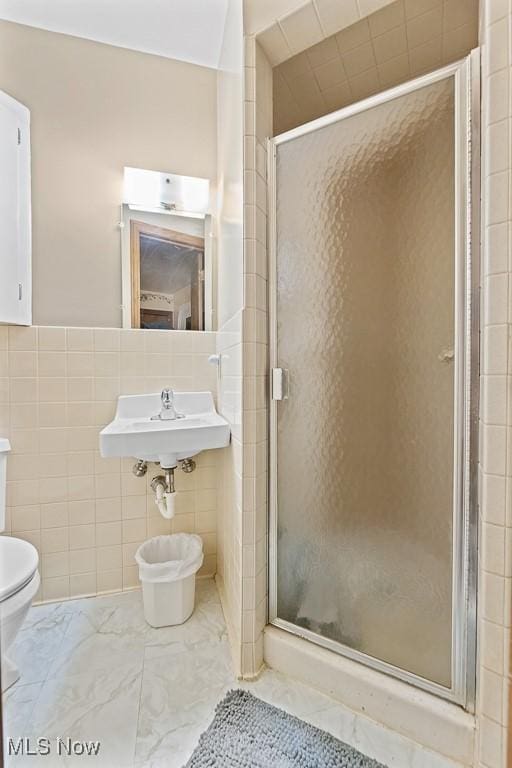 bathroom with sink, toilet, walk in shower, and tile walls