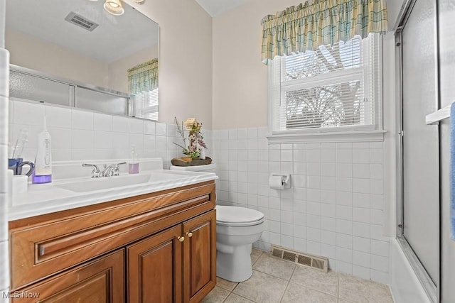 full bathroom with vanity, tile patterned flooring, toilet, enclosed tub / shower combo, and tile walls