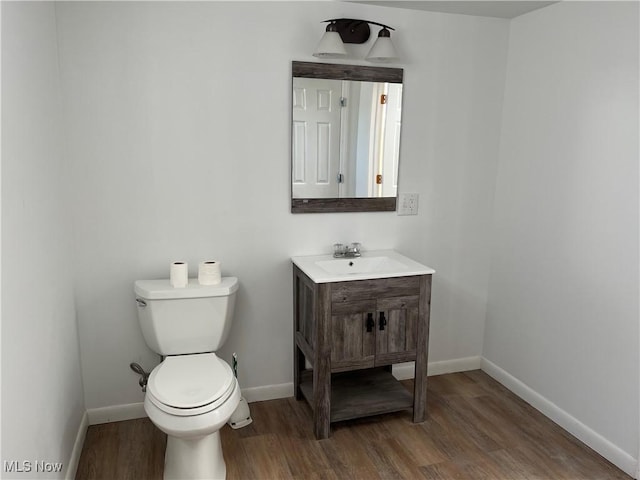 bathroom with toilet, vanity, and hardwood / wood-style flooring