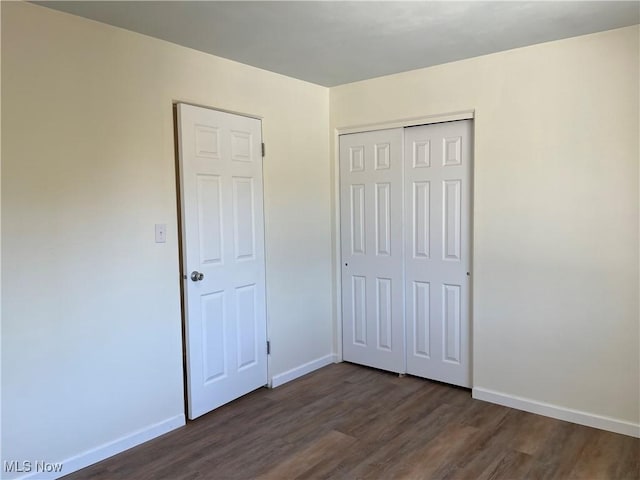 unfurnished bedroom featuring dark hardwood / wood-style flooring and a closet