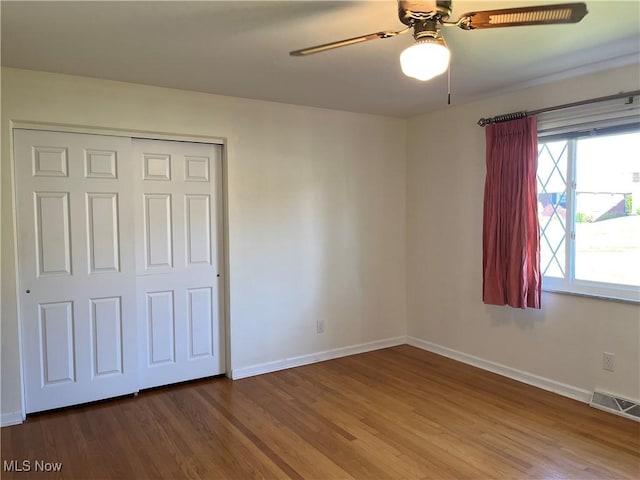 unfurnished bedroom featuring hardwood / wood-style floors, ceiling fan, and a closet