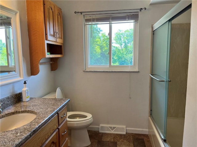 full bathroom featuring shower / bath combination with glass door, vanity, toilet, and a healthy amount of sunlight