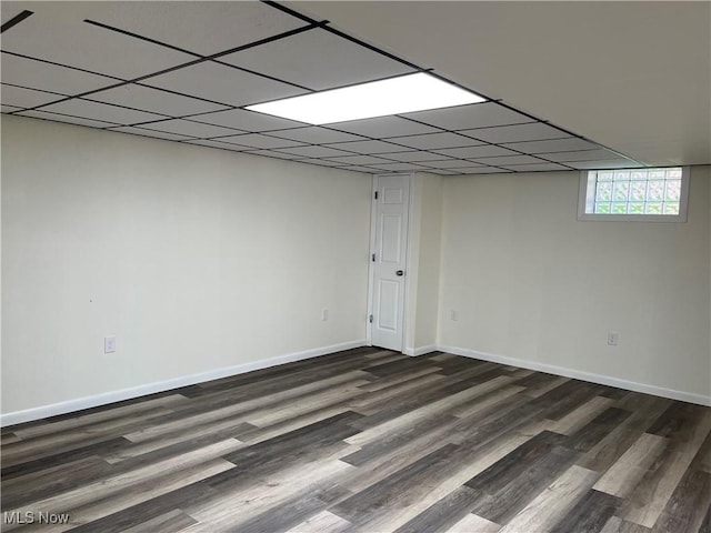 basement with a paneled ceiling and dark hardwood / wood-style floors