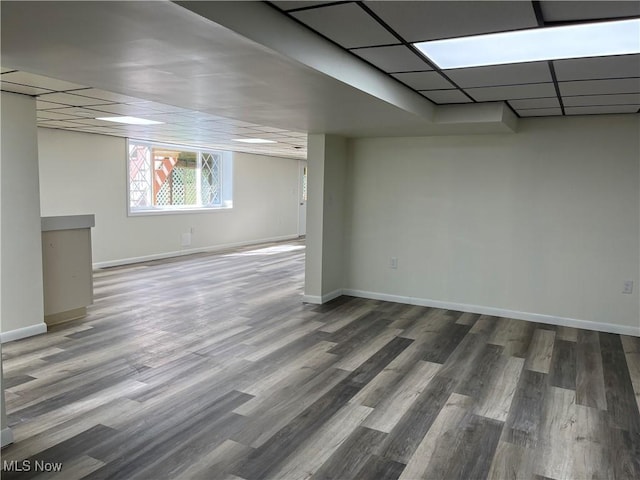 basement with a paneled ceiling and dark wood-type flooring