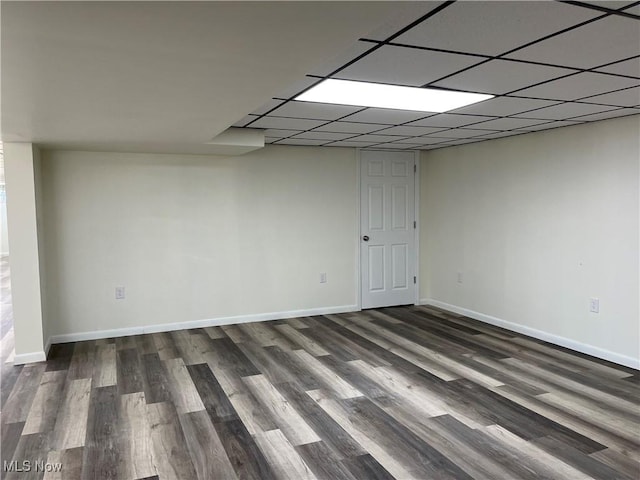 basement featuring a paneled ceiling and dark hardwood / wood-style floors