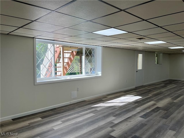 basement with a paneled ceiling, a healthy amount of sunlight, and hardwood / wood-style floors