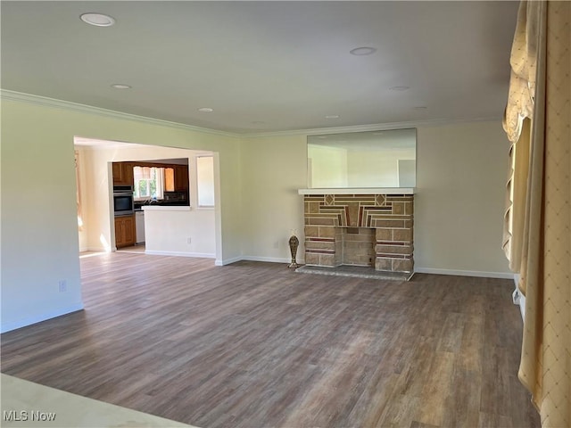 unfurnished living room with dark hardwood / wood-style floors, a stone fireplace, and ornamental molding