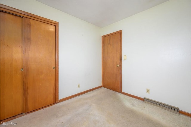 unfurnished bedroom featuring light carpet and a closet