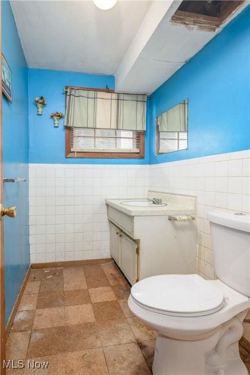 bathroom featuring vanity, toilet, and tile walls