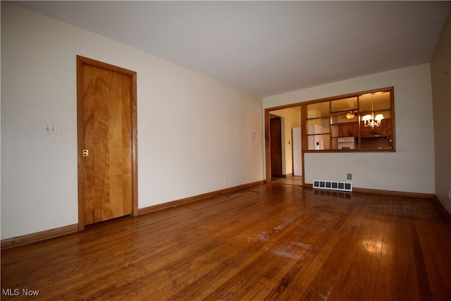 unfurnished living room featuring wood-type flooring and a chandelier