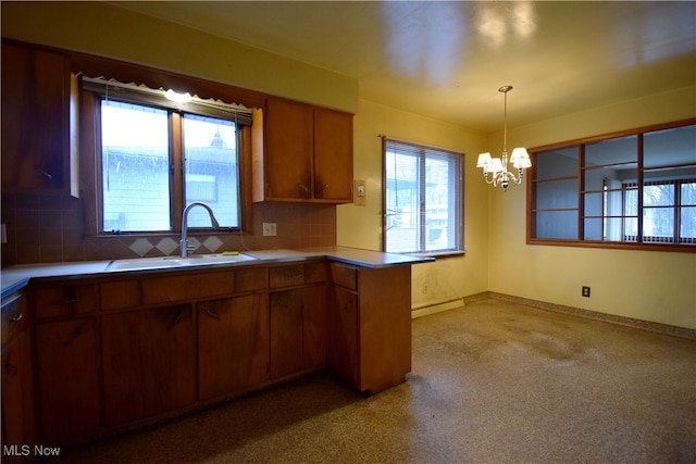 kitchen with backsplash, kitchen peninsula, sink, and hanging light fixtures