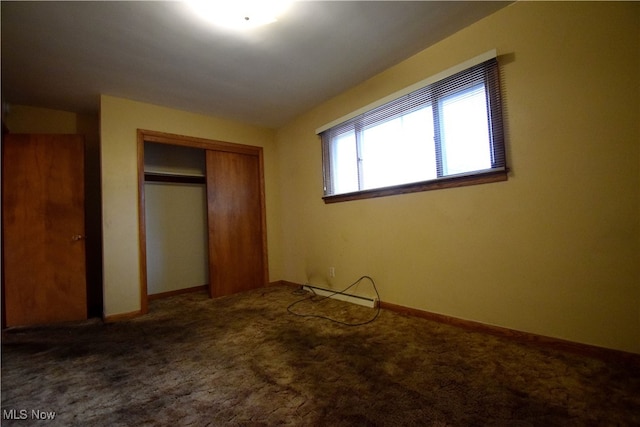 unfurnished bedroom featuring carpet flooring, vaulted ceiling, baseboard heating, and a closet