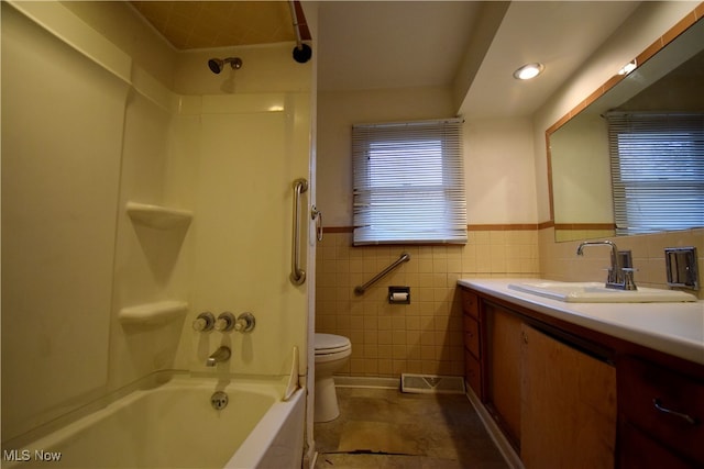 full bathroom featuring tile patterned floors, shower / bath combination, toilet, vanity, and tile walls