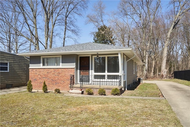 view of front of home with a porch, roof with shingles, concrete driveway, a front yard, and brick siding