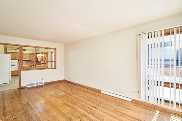 unfurnished living room with visible vents, ceiling fan, baseboards, baseboard heating, and wood-type flooring