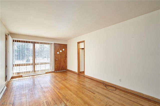 spare room with light wood finished floors, baseboard heating, baseboards, and a baseboard radiator