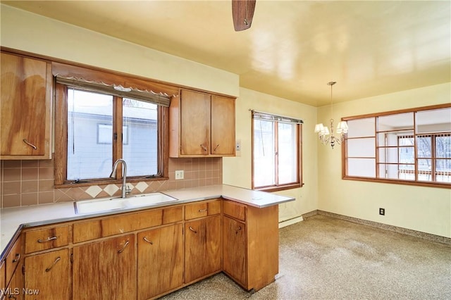 kitchen featuring decorative backsplash, a peninsula, brown cabinets, and a sink