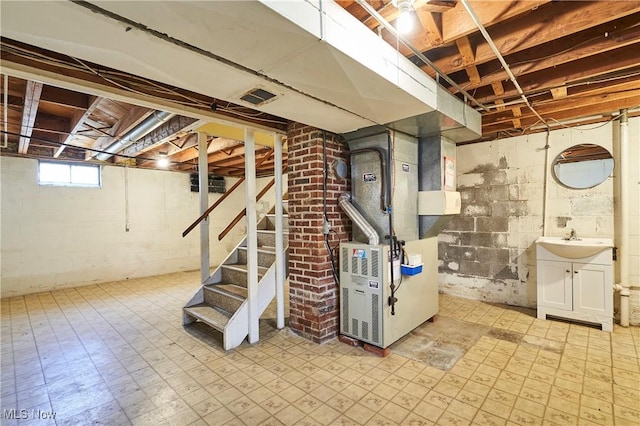 basement featuring tile patterned floors, visible vents, a sink, heating unit, and stairs