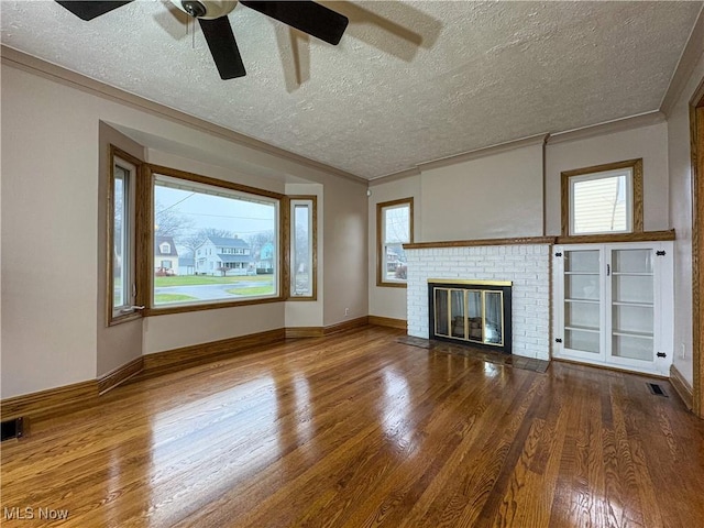 unfurnished living room with hardwood / wood-style floors, a fireplace, ornamental molding, and a textured ceiling