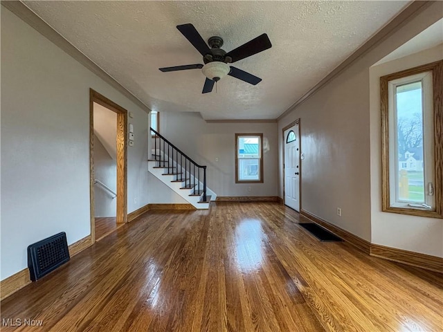 interior space with hardwood / wood-style flooring, ceiling fan, ornamental molding, and a textured ceiling