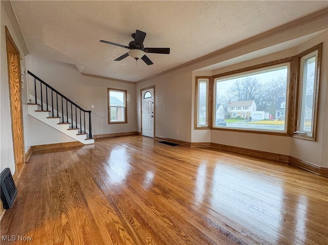 entryway with ceiling fan, heating unit, ornamental molding, light hardwood / wood-style floors, and a textured ceiling