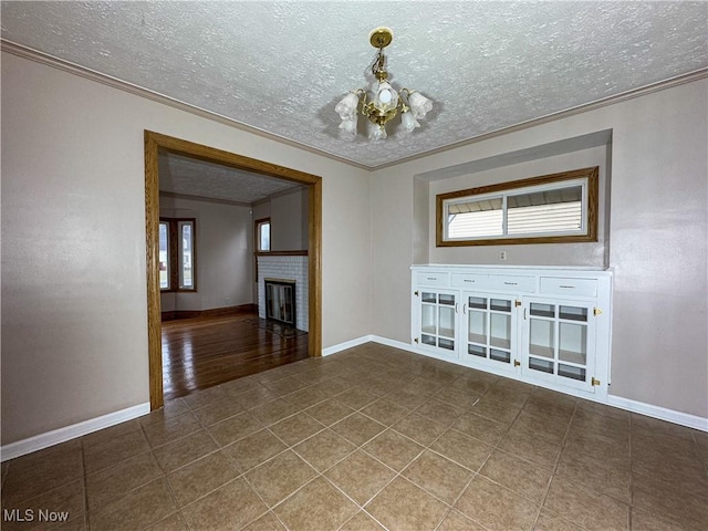 unfurnished living room with a brick fireplace, crown molding, tile patterned floors, and a textured ceiling