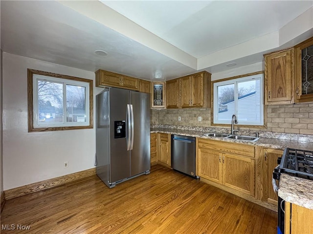 kitchen featuring appliances with stainless steel finishes, light hardwood / wood-style floors, sink, and decorative backsplash