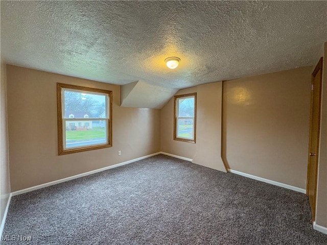 bonus room with vaulted ceiling, a textured ceiling, and carpet