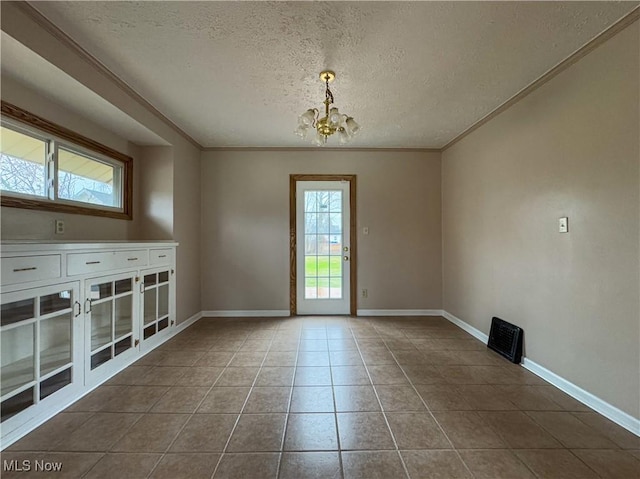 tiled empty room featuring ornamental molding, a textured ceiling, and a notable chandelier