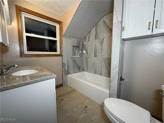 full bathroom featuring hardwood / wood-style floors, vanity, a textured ceiling, toilet, and tiled shower / bath