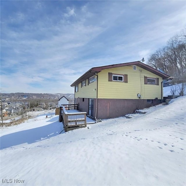 view of snowy exterior with a garage and a wooden deck