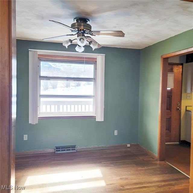 spare room featuring a ceiling fan, baseboards, visible vents, and wood finished floors