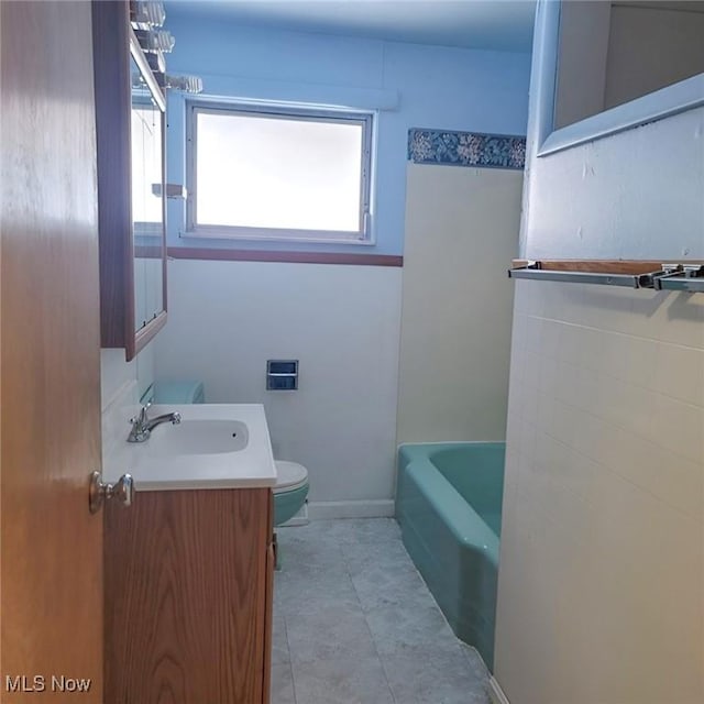 bathroom featuring a washtub, toilet, vanity, baseboards, and tile patterned floors