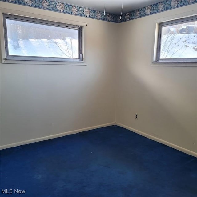 unfurnished room with dark colored carpet and baseboards