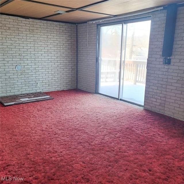 carpeted spare room with brick wall