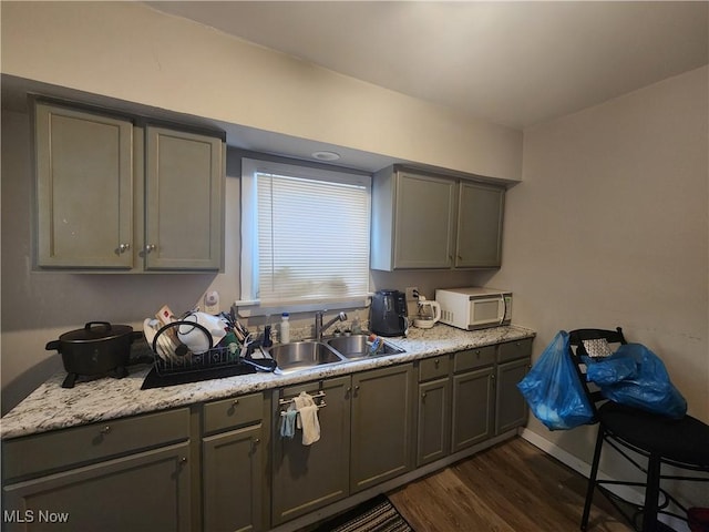 kitchen featuring gray cabinetry, dark hardwood / wood-style floors, light stone countertops, and sink