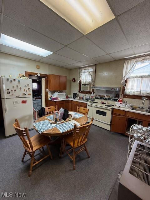 kitchen featuring white appliances, dark carpet, a paneled ceiling, and sink