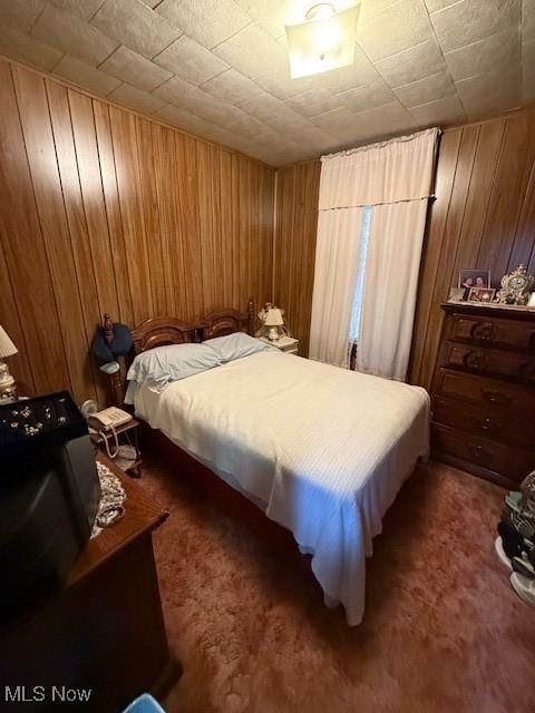 carpeted bedroom featuring wooden walls