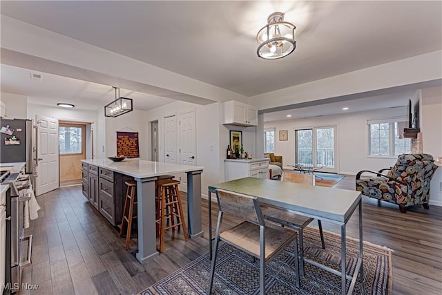 kitchen with a center island, white cabinets, decorative light fixtures, dark hardwood / wood-style flooring, and stainless steel appliances