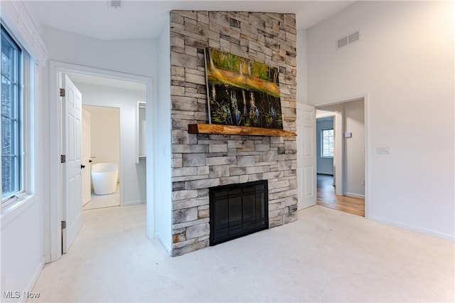 living room featuring a stone fireplace, light carpet, and lofted ceiling