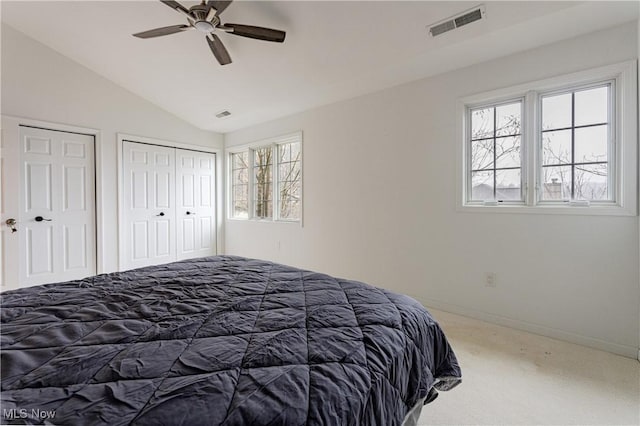 bedroom featuring carpet flooring, multiple closets, ceiling fan, and lofted ceiling