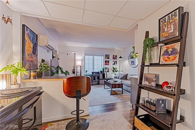 interior space with wood-type flooring, a wall unit AC, and a drop ceiling