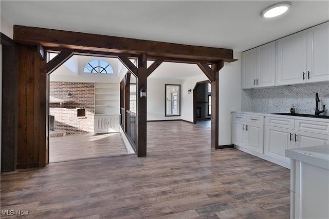 kitchen with wood-type flooring, tasteful backsplash, white cabinetry, and sink