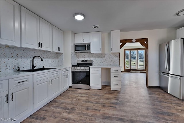 kitchen featuring white cabinets, decorative backsplash, stainless steel appliances, and dark wood-type flooring