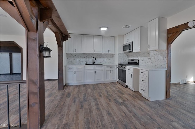 kitchen with hardwood / wood-style floors, sink, white cabinets, and stainless steel appliances